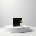 Gris Montaigne Musc Tahara Parfum (10ml) in a clear glass bottle with a gold cap, next to its dark green box with gold lettering.