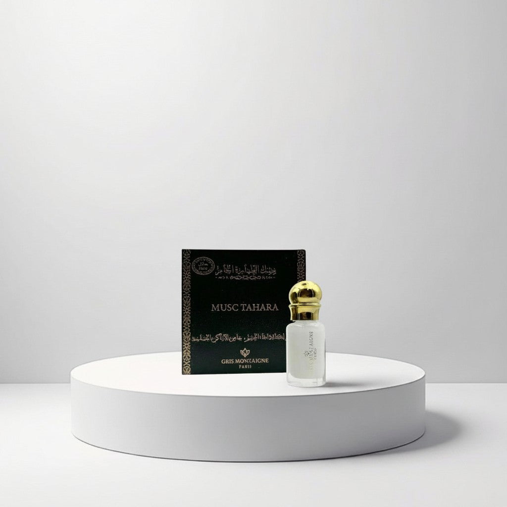 Gris Montaigne Musc Tahara Parfum (10ml) in a clear glass bottle with a gold cap, next to its dark green box with gold lettering.